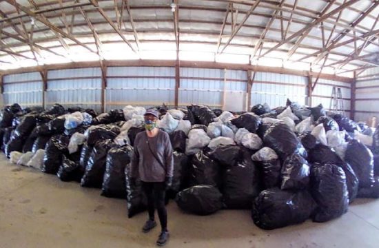 Woman standing in front of bags of cans