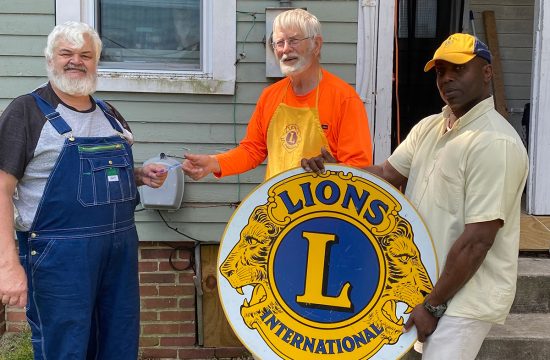 MAn holding large Lions Clubs International sign