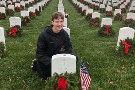 Tenn posing with gravestones he has honored with flags and flowers