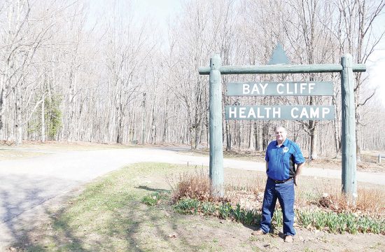 Lion stands in front of sign for camp
